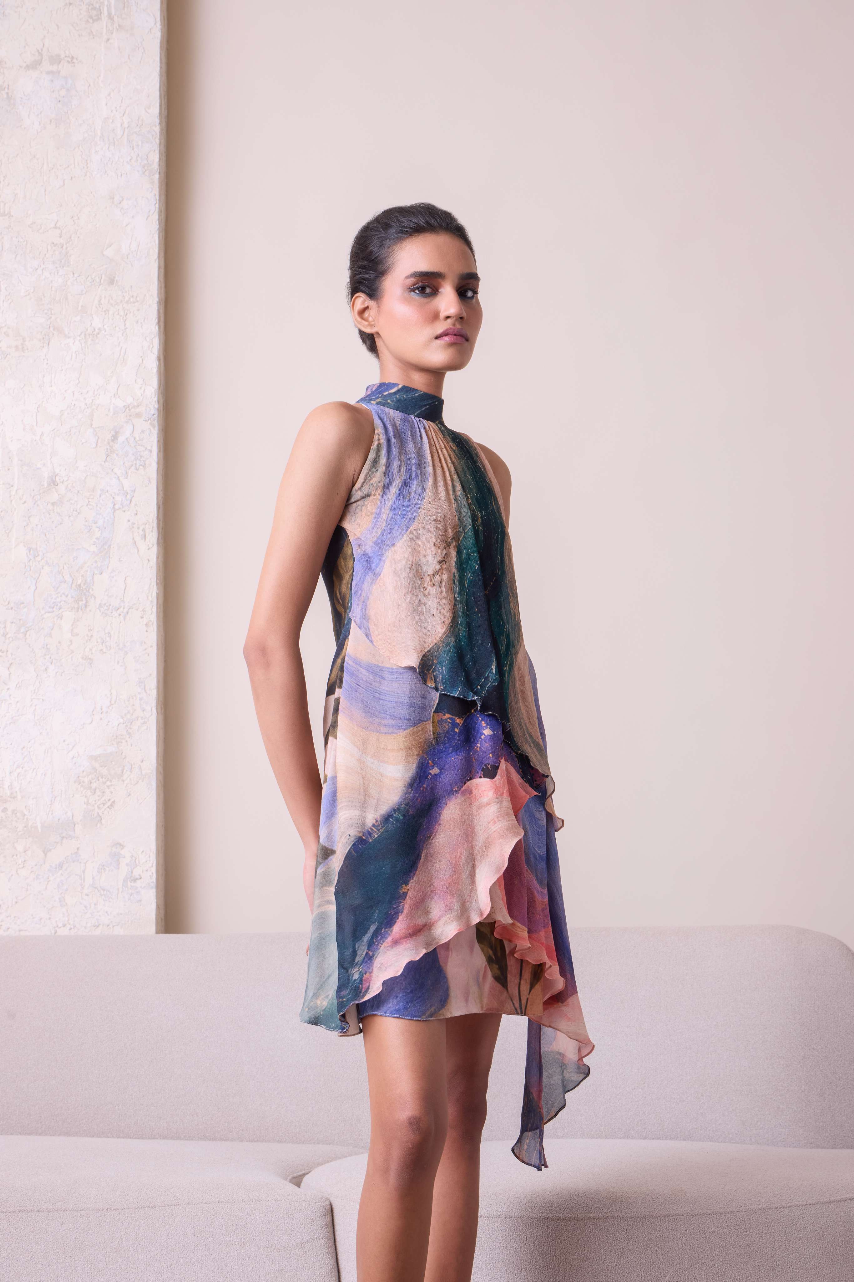 Simor Solistice high neck tiered cascade dress displayed on a hanger, featuring flowing layers and a high neckline.